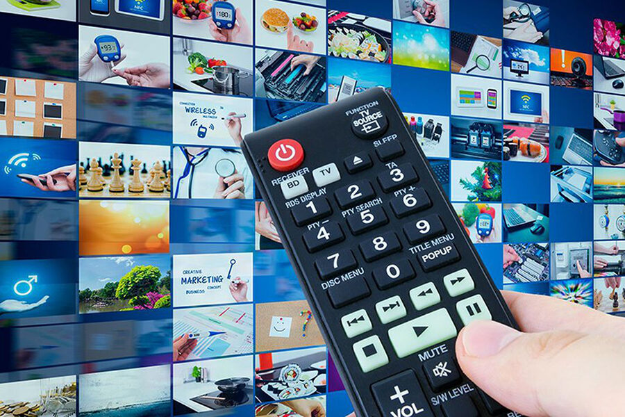 Spot publicitaire multi-écrans : télécommande devant une mosaïque de contenus vidéo digitaux