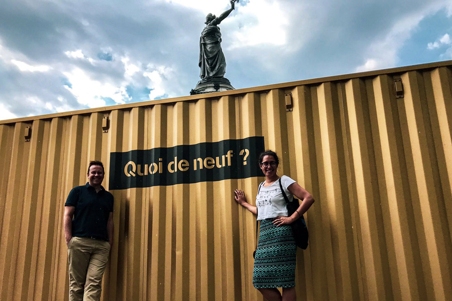 Tournage vidéo d'entreprise à Paris : deux personnes devant un container floqué « Quoi de neuf »