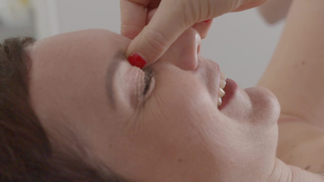 Spot publicitaire Sigvaris : portrait de Julie souriante, la main près du visage en gros plan
