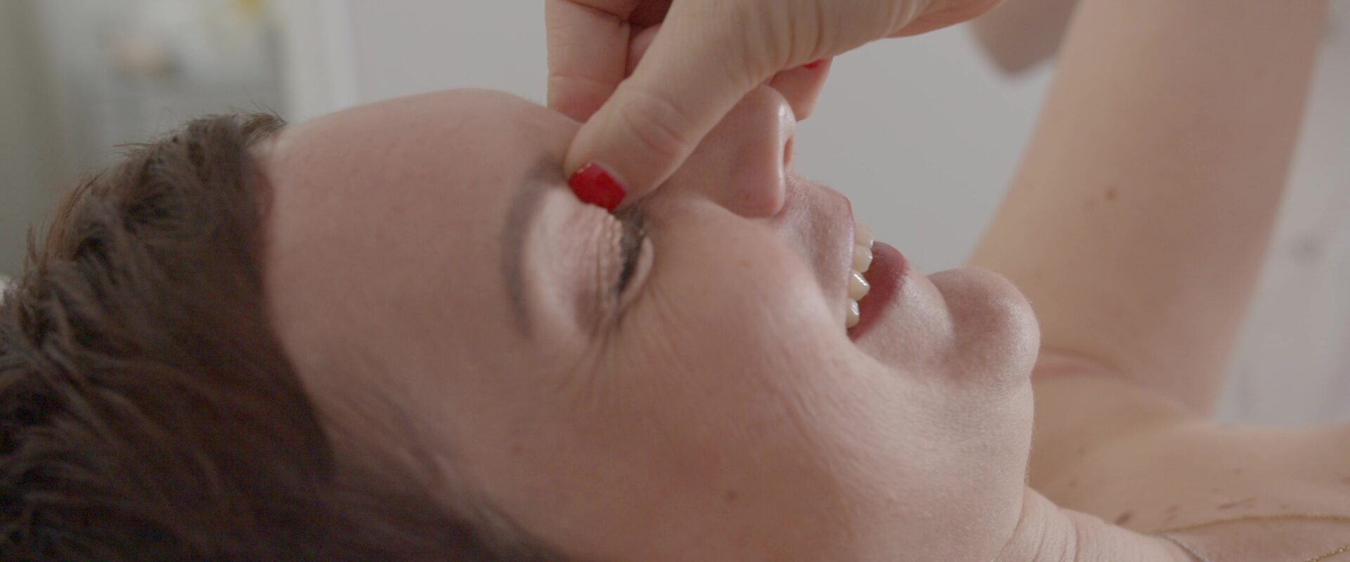 Spot publicitaire Sigvaris : portrait de Julie souriante, la main près du visage en gros plan