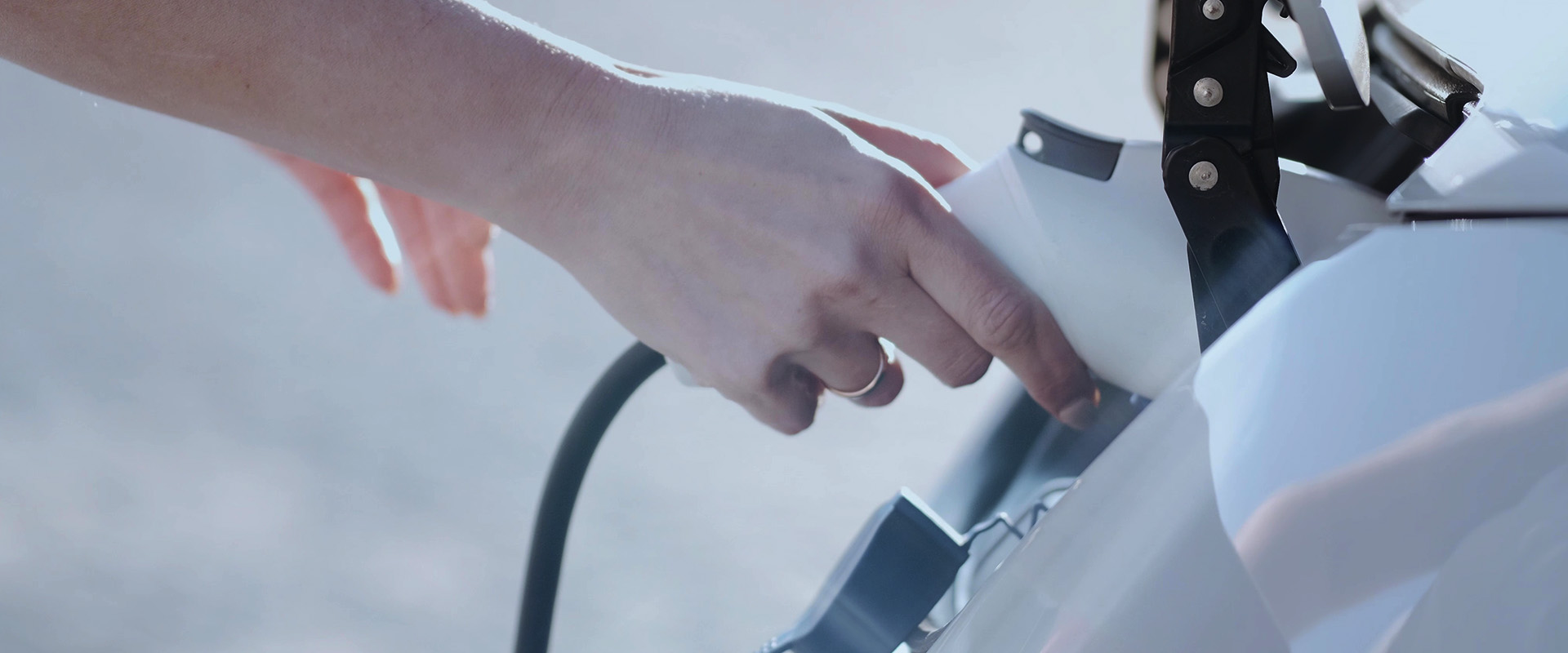 Film institutionnel Optimum Automotive : main branchant une borne de recharge sur véhicule électrique