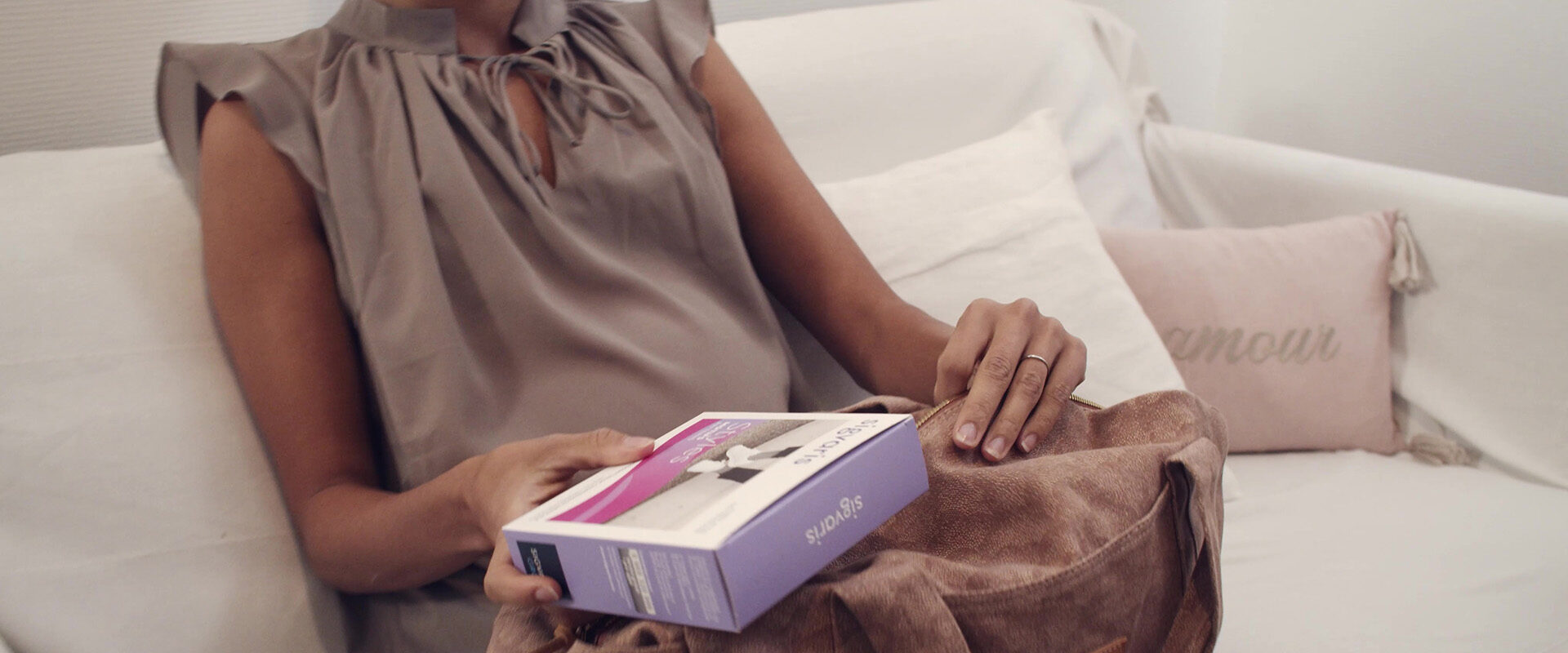Spot publicitaire Sigvaris sur la maternité : une femme sort une boîte de produit de son sac sur un canapé