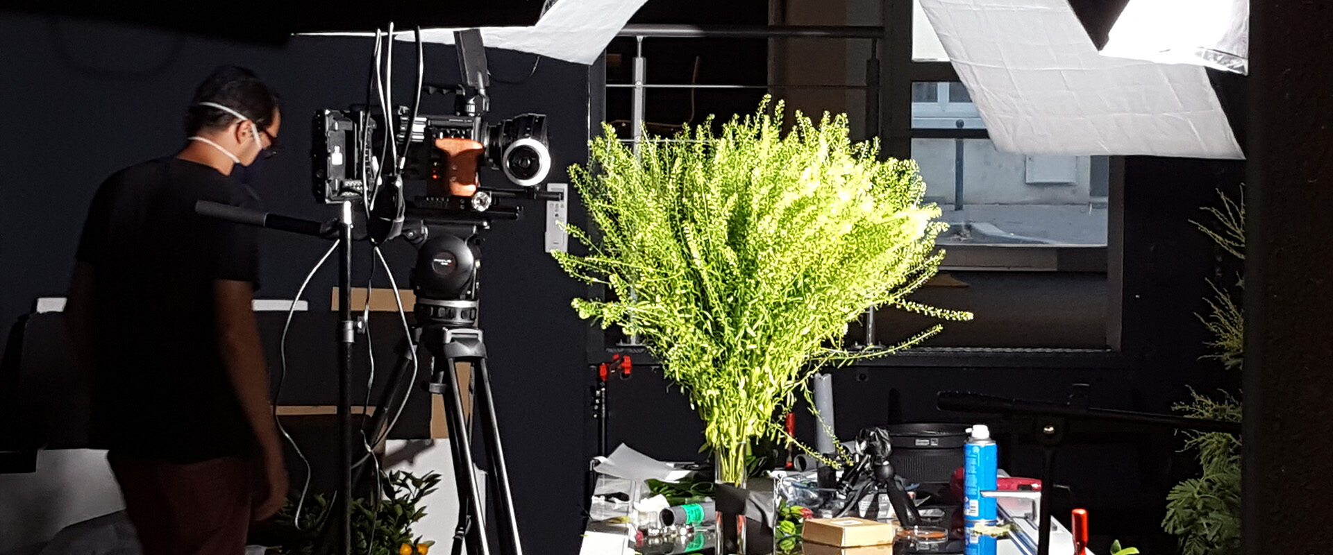 Tournage du film de marque Mane Group : cadreur réglant sa caméra en studio près d'une composition végétale