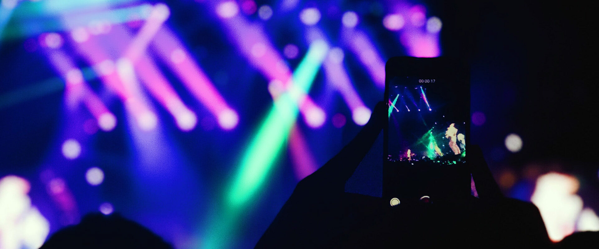 Aftermovie pour MYM : smartphone filmant un concert aux jeux de lumière colorés dans la foule