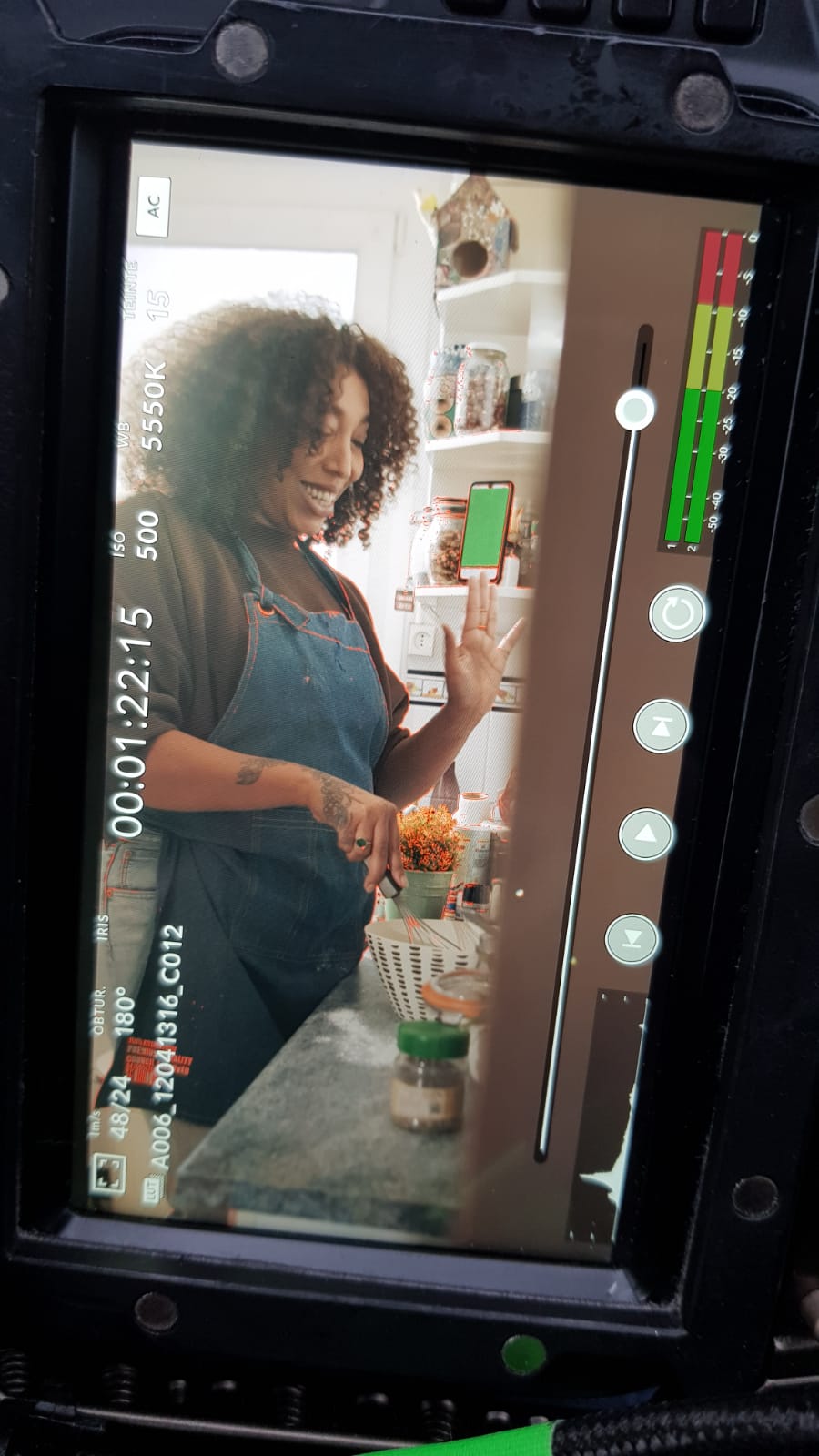 Tournage vidéo d'entreprise MYM : moniteur caméra filmant une femme tenant un smartphone en cuisine