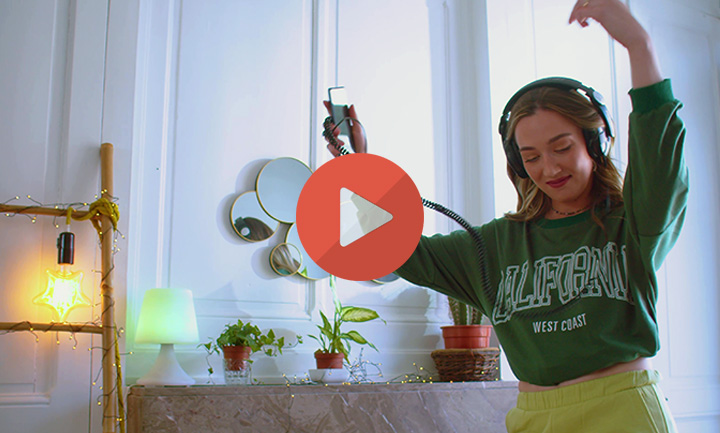 Spot publicitaire MYM : jeune femme casque sur les oreilles dansant dans un salon lumineux