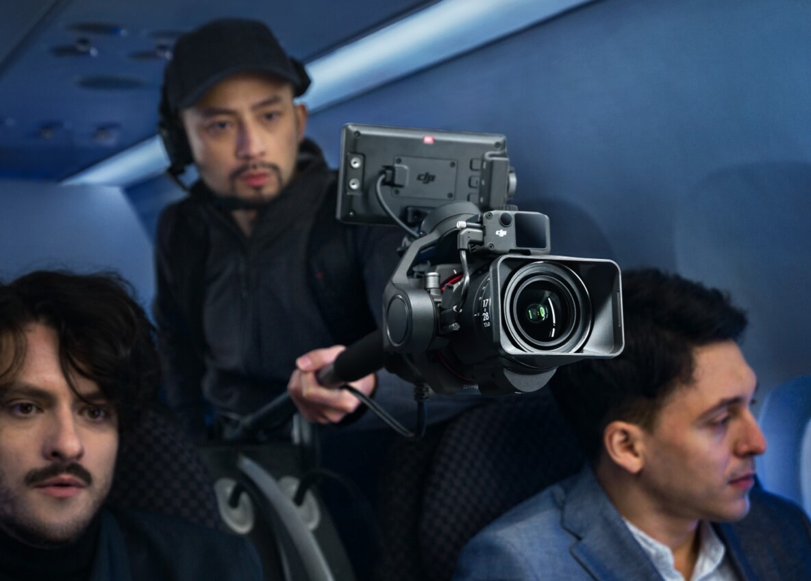 Tournage vidéo d'entreprise en avion : cadreur au Ronin 4D entouré de deux comédiens