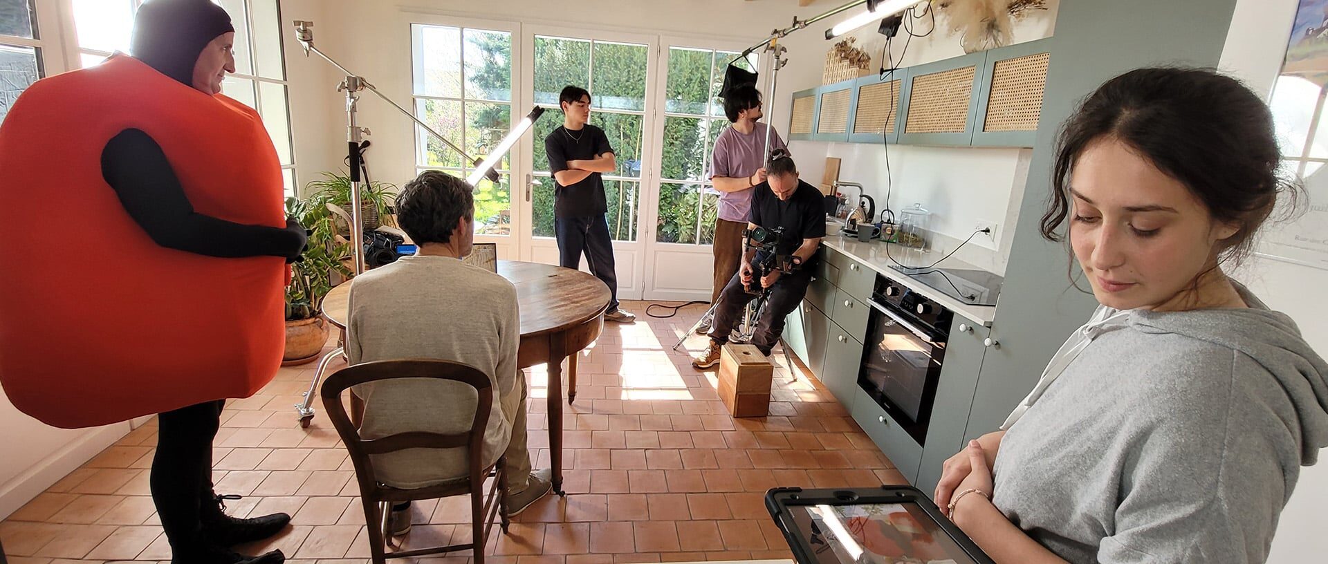Tournage du spot publicitaire Bail Rénov' : comédien costumé en fruit dans une cuisine avec l'équipe technique