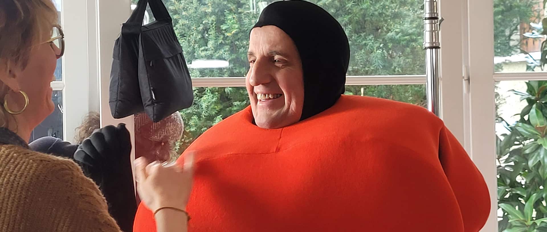 Tournage du spot publicitaire Bail Rénov' : homme en costume orange souriant lors d'une scène décalée