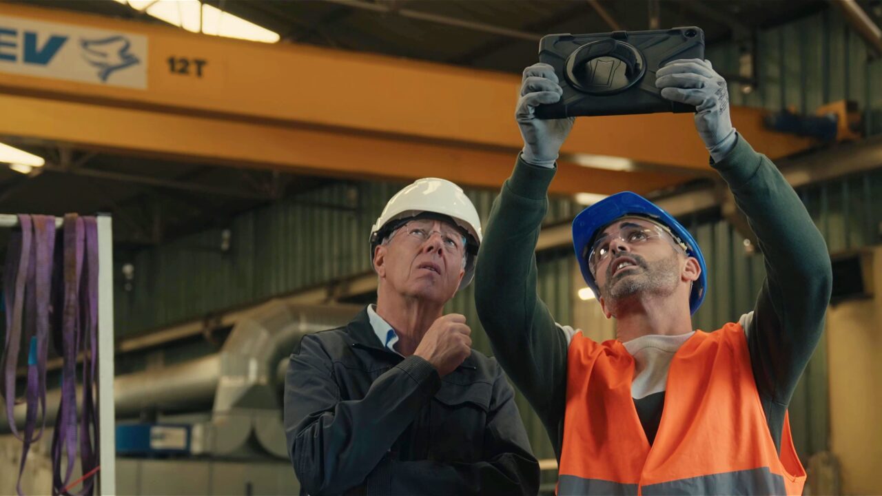 Techniciens en casque inspectant une structure en usine avec une tablette, film de marque Alkera, gestion des sinistres