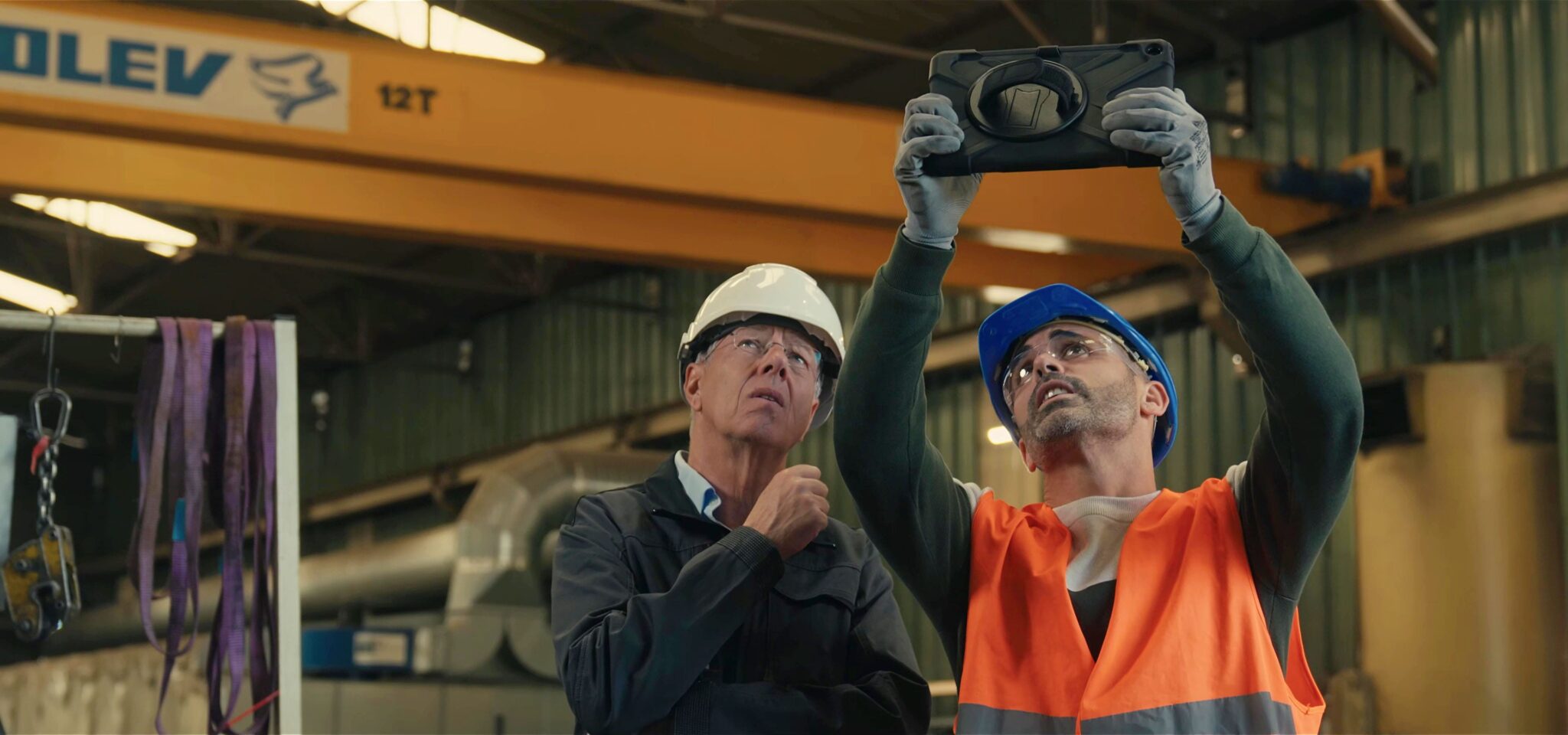 Techniciens en casque inspectant une structure en usine avec une tablette, film de marque Alkera, gestion des sinistres