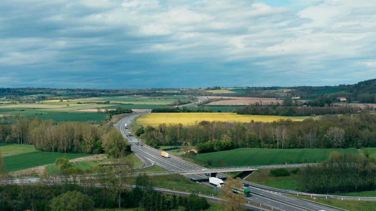 Vue aérienne d'une autoroute avec camions traversant champs et bocage, film d'entreprise APRR sur les mobilités