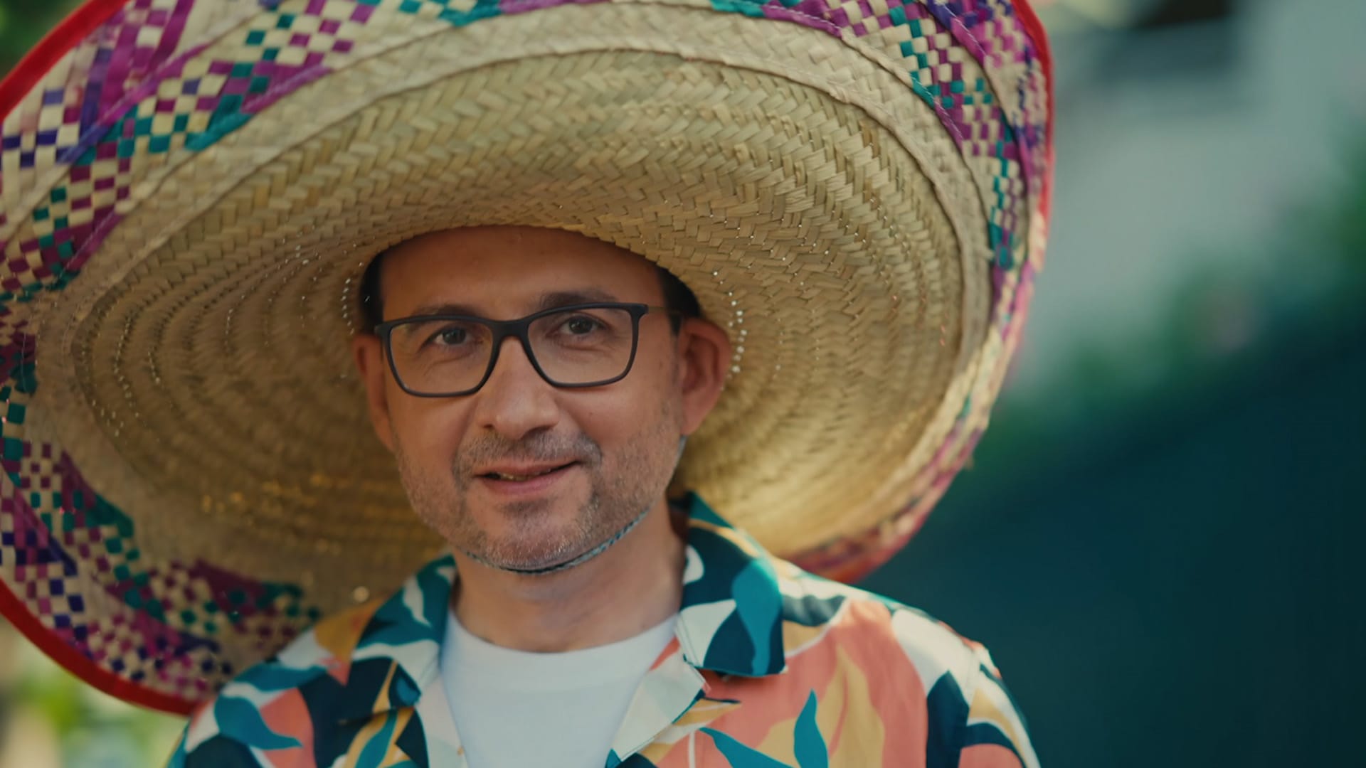 Homme souriant en sombrero coloré, ambiance feel good pour la campagne vidéo Avatacar, réseau de garages
