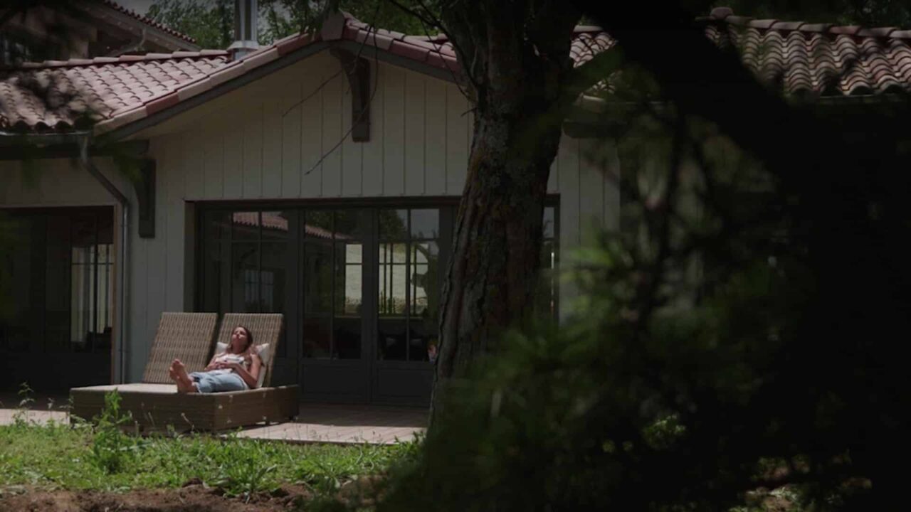 Femme en terrasse d'une maison filmée depuis le jardin, vidéo institutionnelle Climax, enseigne de distribution