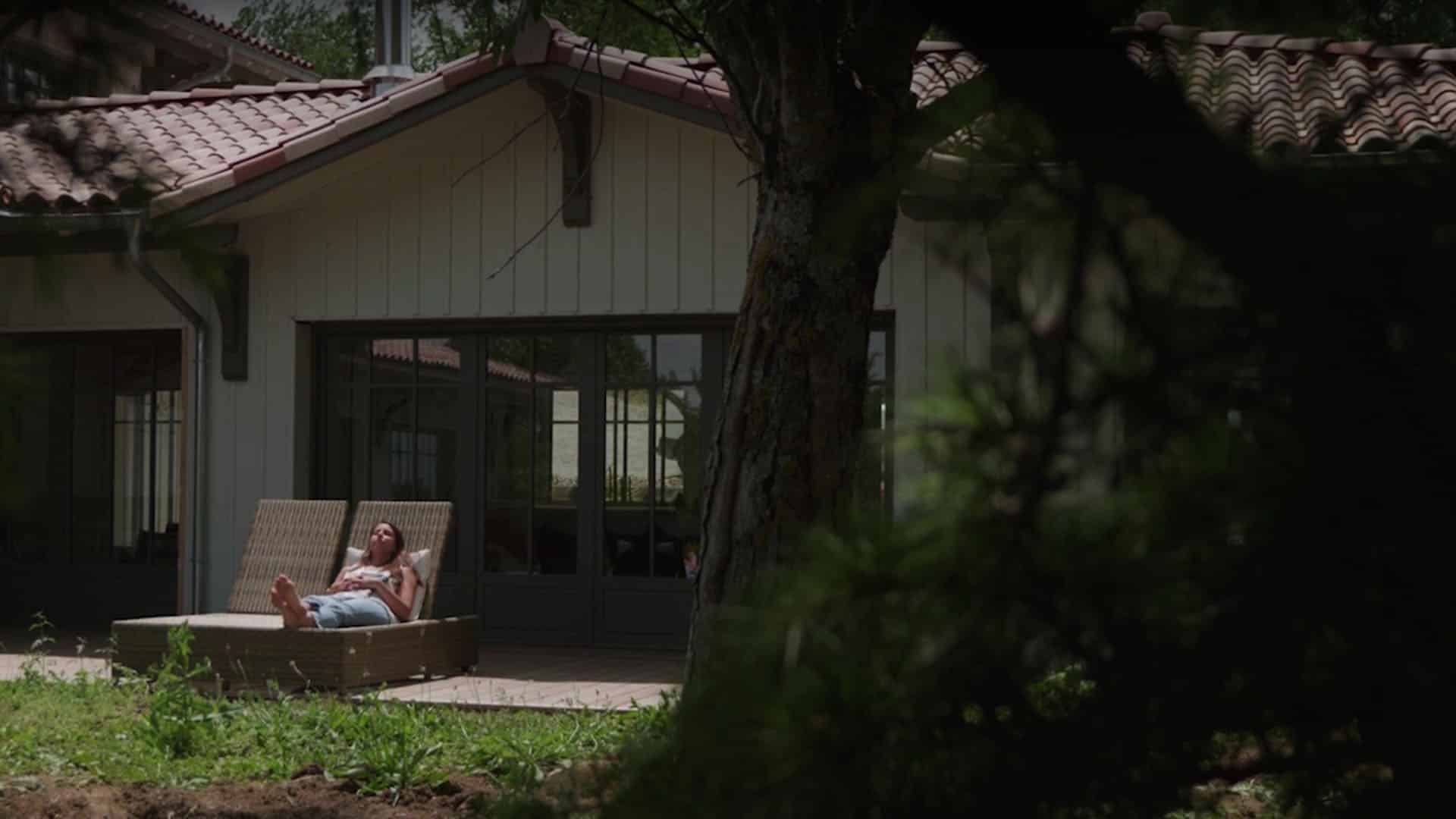 Femme en terrasse d'une maison filmée depuis le jardin, vidéo institutionnelle Climax, enseigne de distribution