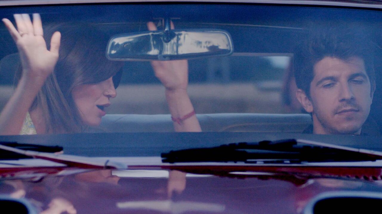 Couple en voiture ancienne, bras levé, ambiance road-trip — film de marque pour les 85 ans d'EFI Automotive, équipementier automobile