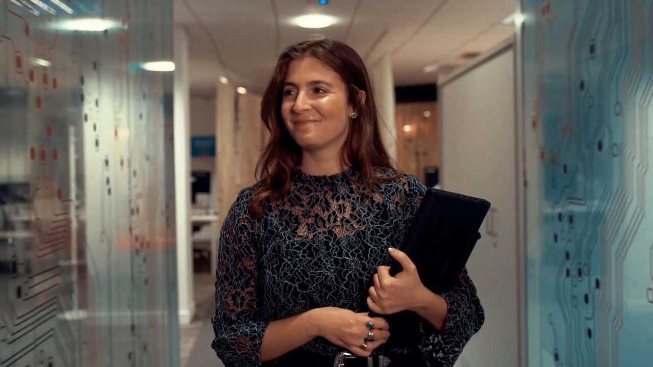 Collaboratrice souriante en couloir de bureau, tablette en main, film d'onboarding ENGIE GBS, énergie