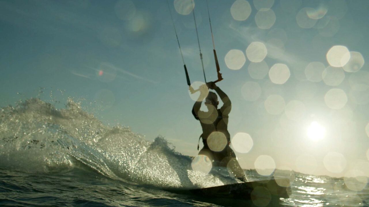 Kitesurfeur en silhouette sur une vague au soleil, film d'entreprise Everial, groupe de services