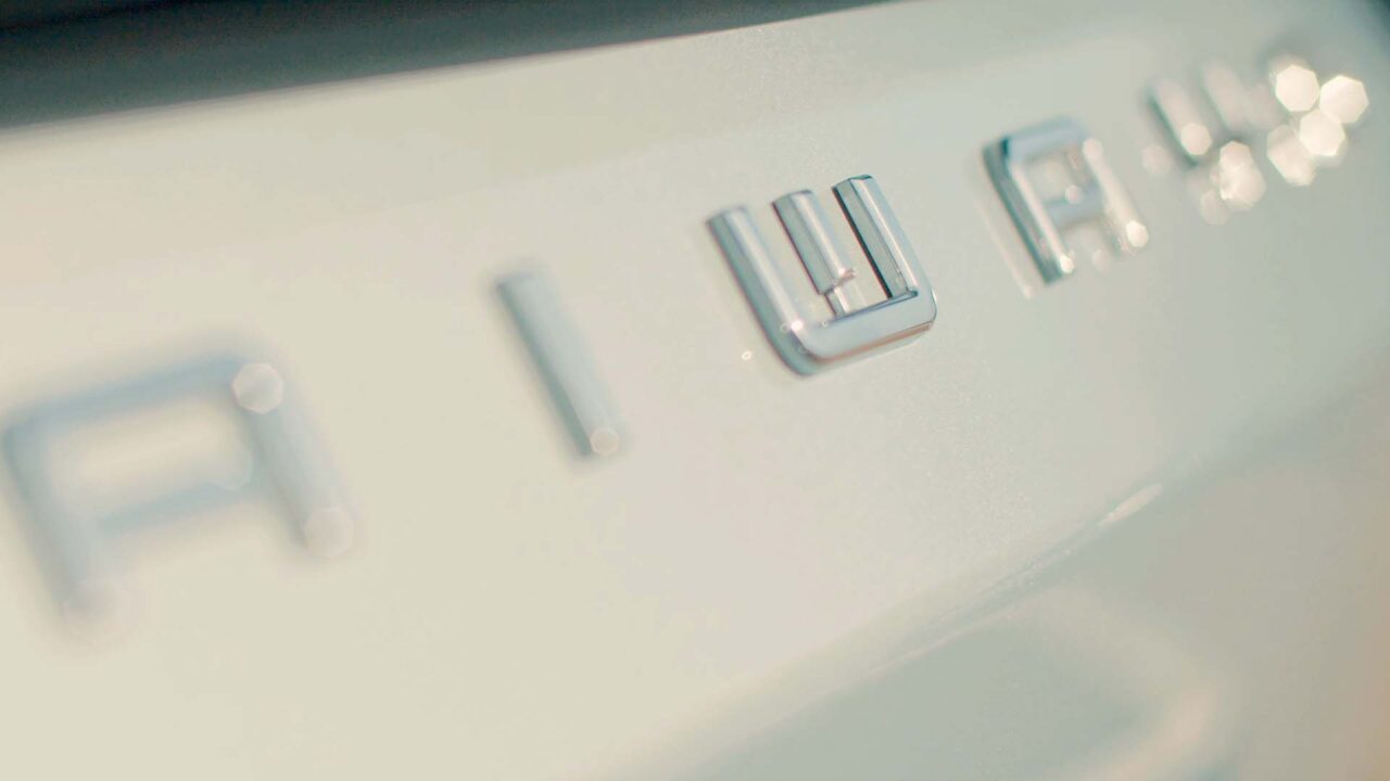 Emblème chromé Aiways sur carrosserie blanche, film de marque pour le partenariat Feu Vert X Aiways en mobilité électrique