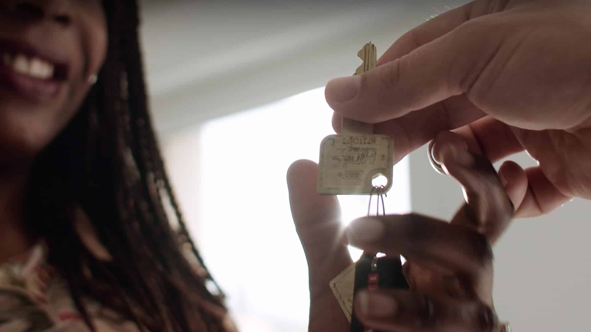 Remise de clés en contre-plongée lumineuse, jeune femme souriante — film d'entreprise Lamotte Immobilier, promoteur immobilier