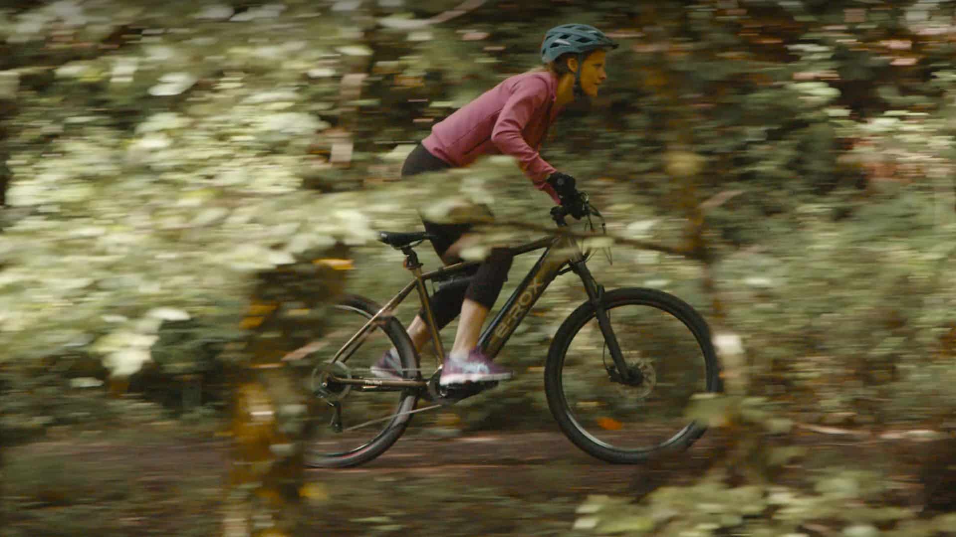 Cycliste sur vélo électrique E-Rox Feu Vert en forêt, enseigne de distribution, film publicitaire