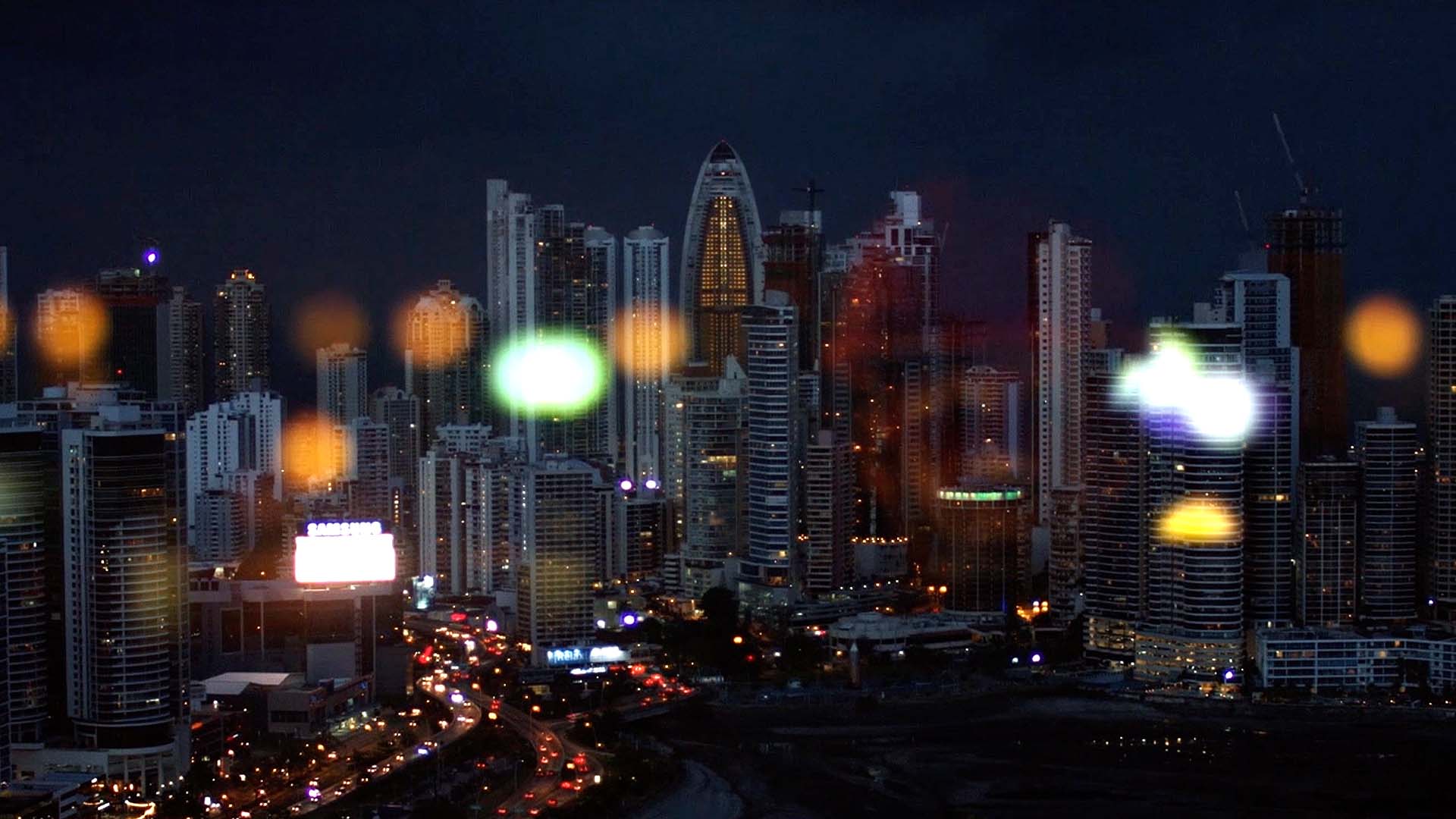 Skyline nocturne aux reflets colorés illustrant la dimension internationale de NGE, groupe BTP, dans son film de marque