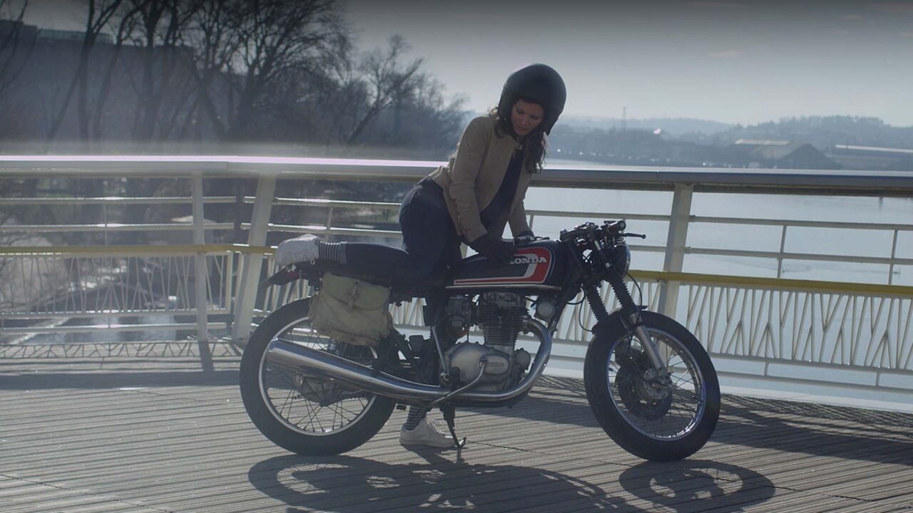 Motarde sur Honda vintage au bord d'un fleuve, publicité vidéo Sigvaris Marinière, compression médicale