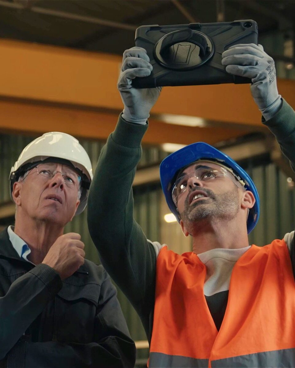 Techniciens en casque inspectant une structure en usine avec une tablette, film de marque Alkera, gestion des sinistres