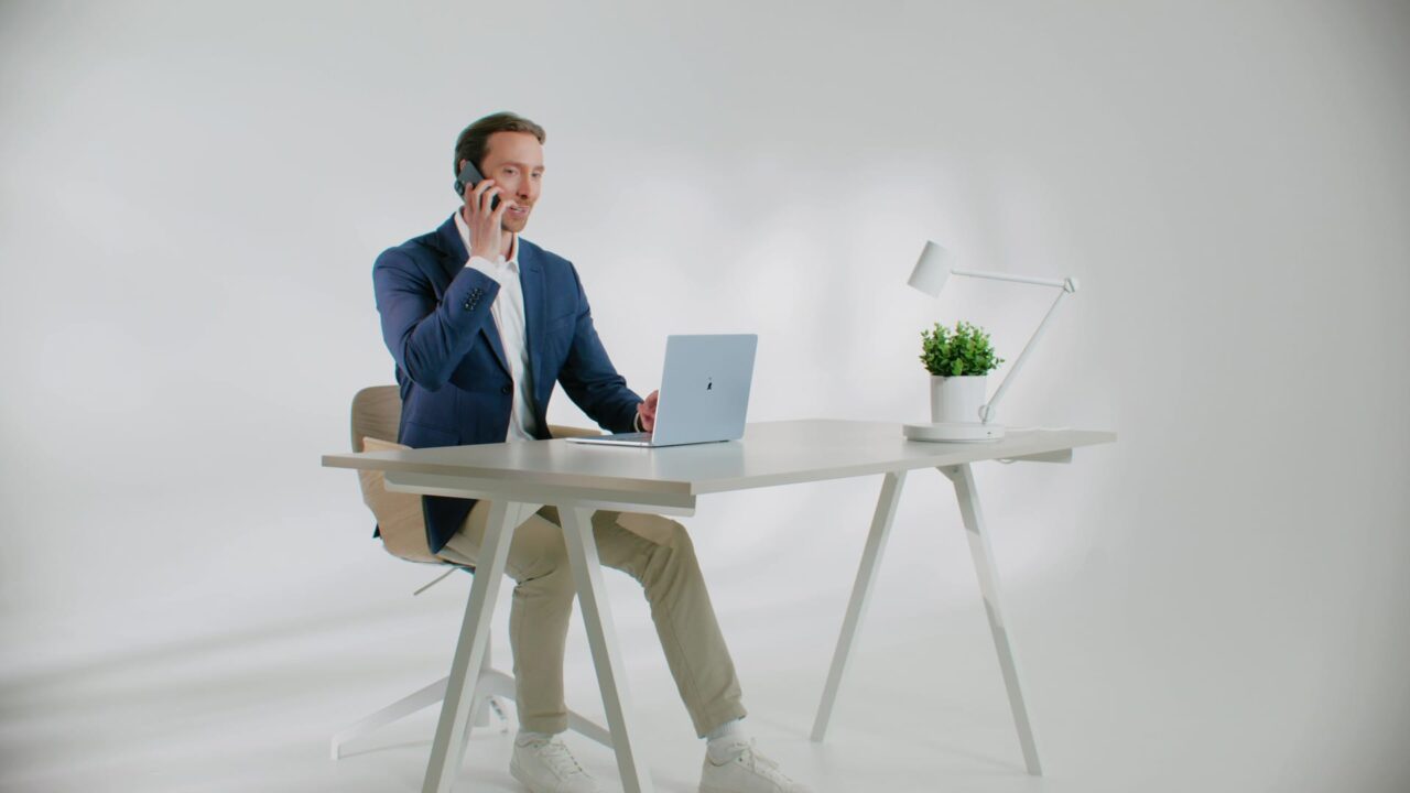 Homme en veste bleue téléphonant devant un laptop, spot TV pour Econocom Easi, services IT