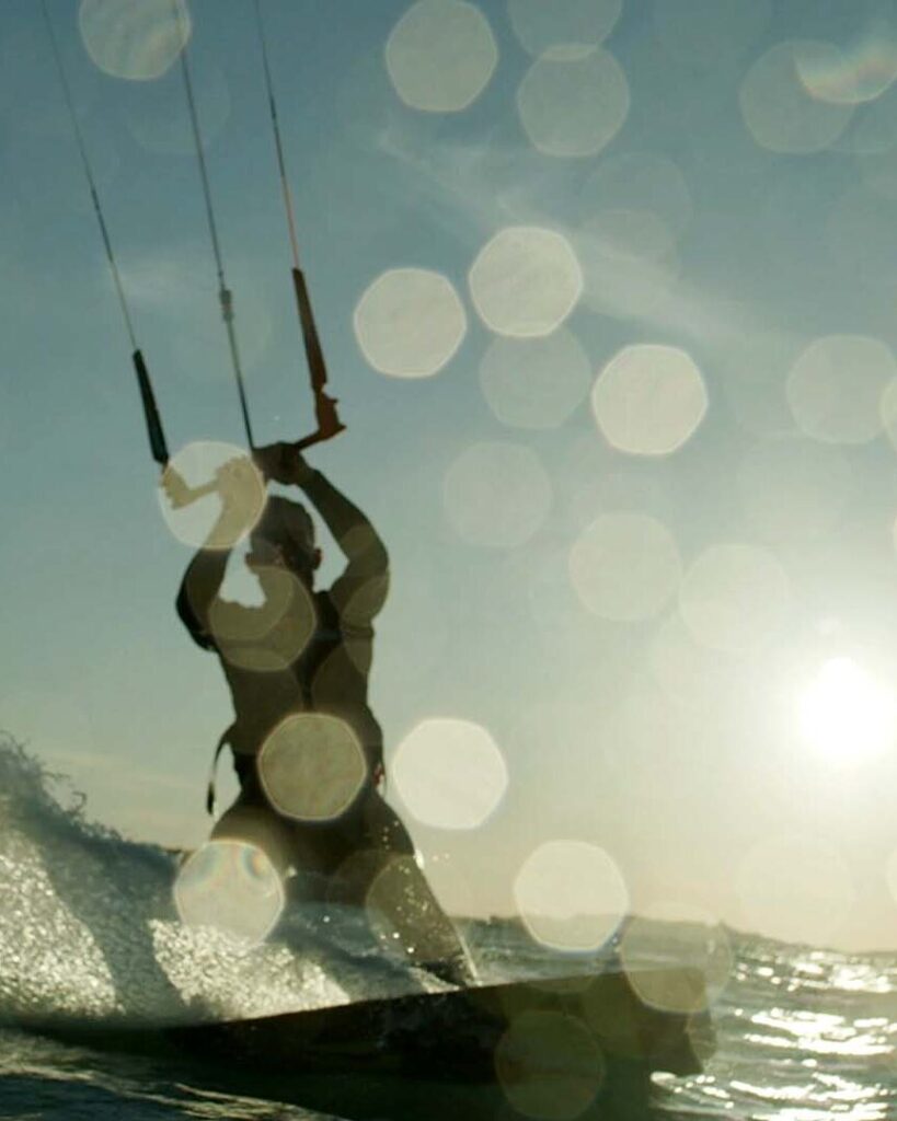 Kitesurfeur en silhouette sur une vague au soleil, film d'entreprise Everial, groupe de services