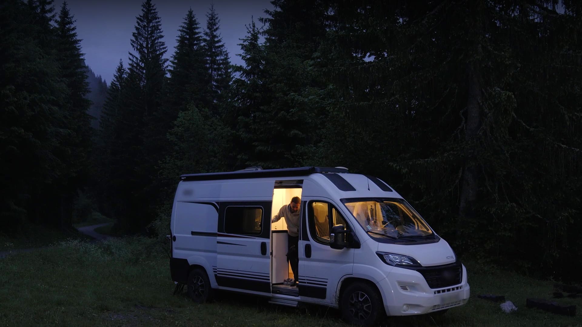 Fourgon aménagé éclairé en forêt la nuit, homme à la porte — spot TV Feu Vert Van Life, enseigne de distribution automobile