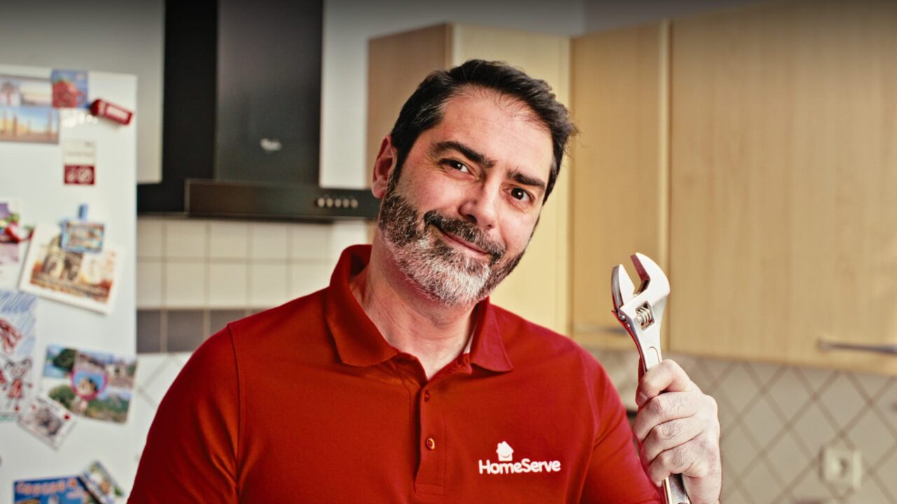 Technicien HomeServe, clé à molette en main dans une cuisine, film de marque dépannage habitat