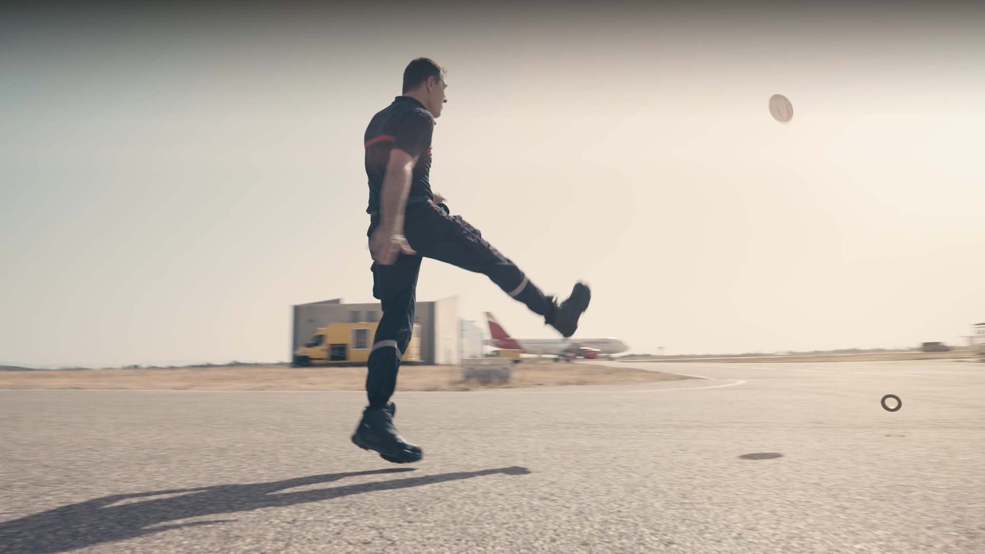 Agent aéroportuaire bottant un ballon de rugby sur le tarmac — Lyon Aéroports, film de marque