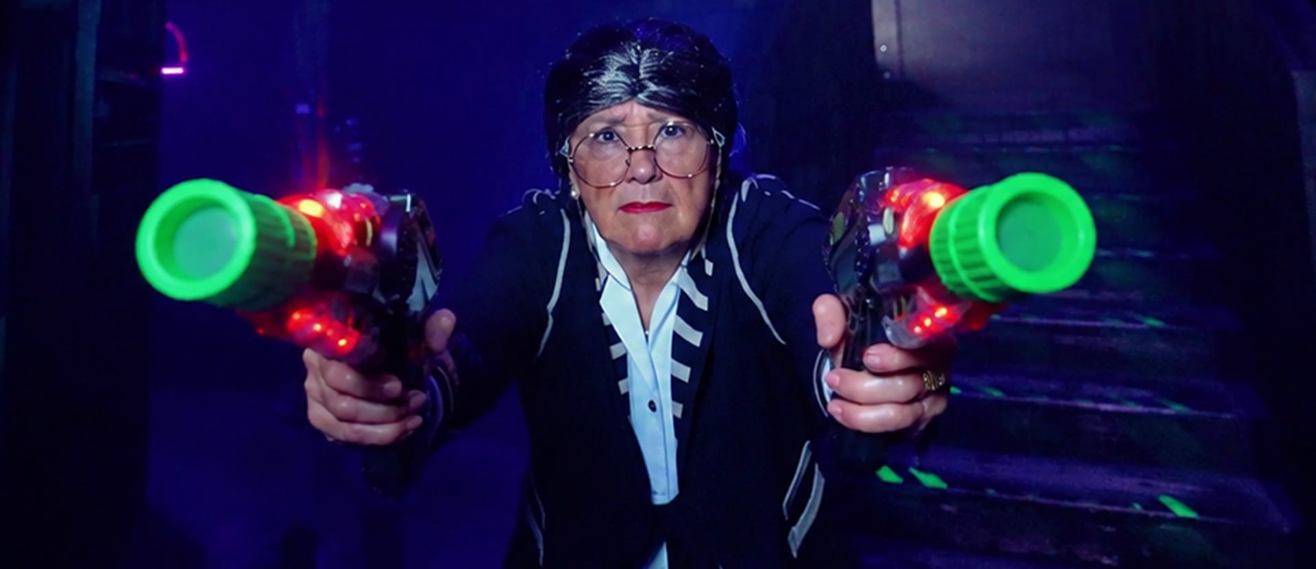 Spot publicitaire Megazone : femme armée de deux pistolets laser dans une arène fluo