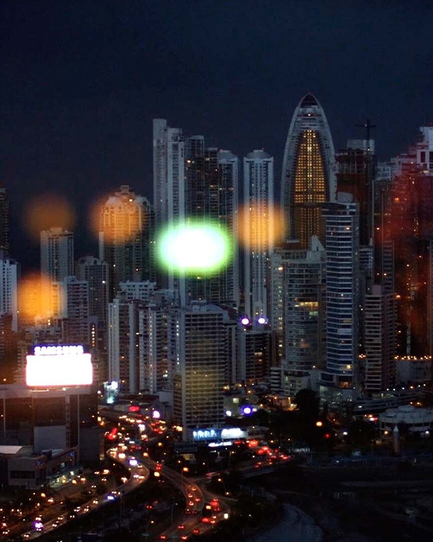 Skyline nocturne aux reflets colorés illustrant la dimension internationale de NGE, groupe BTP, dans son film de marque