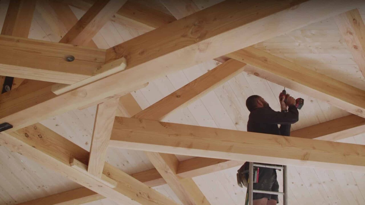 Charpentier vissant des solives sous une charpente bois, spot TV Rocket, fabricant de vis