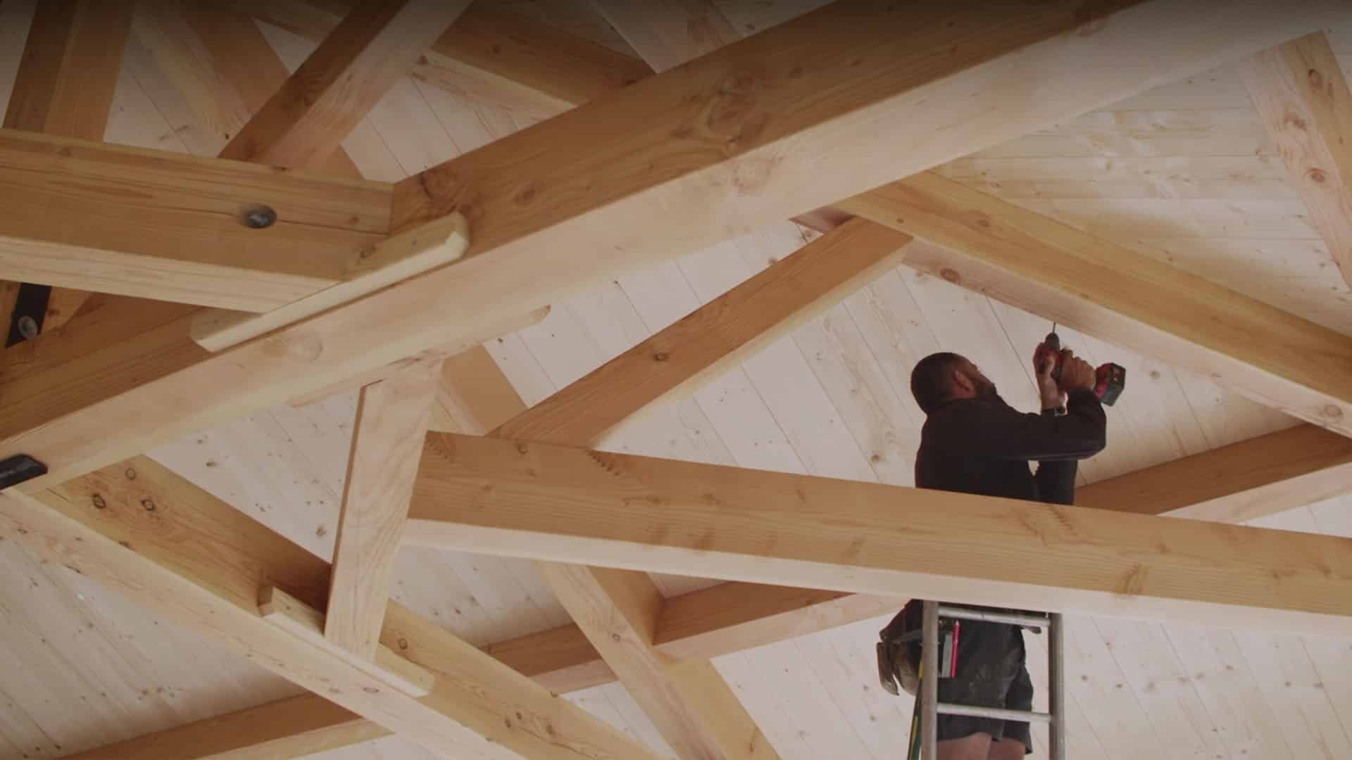 Charpentier vissant des solives sous une charpente bois, spot TV Rocket, fabricant de vis